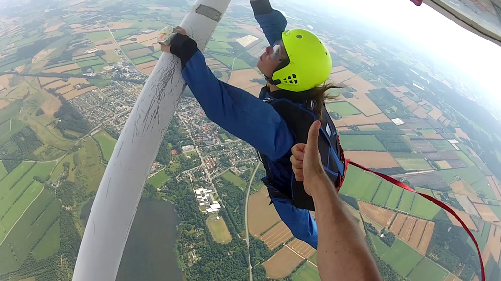 En elev hænger under stræberen af et fly, klar til at give slip og tage sit første solospring med en static line, som automatisk udløser faldskærmen.